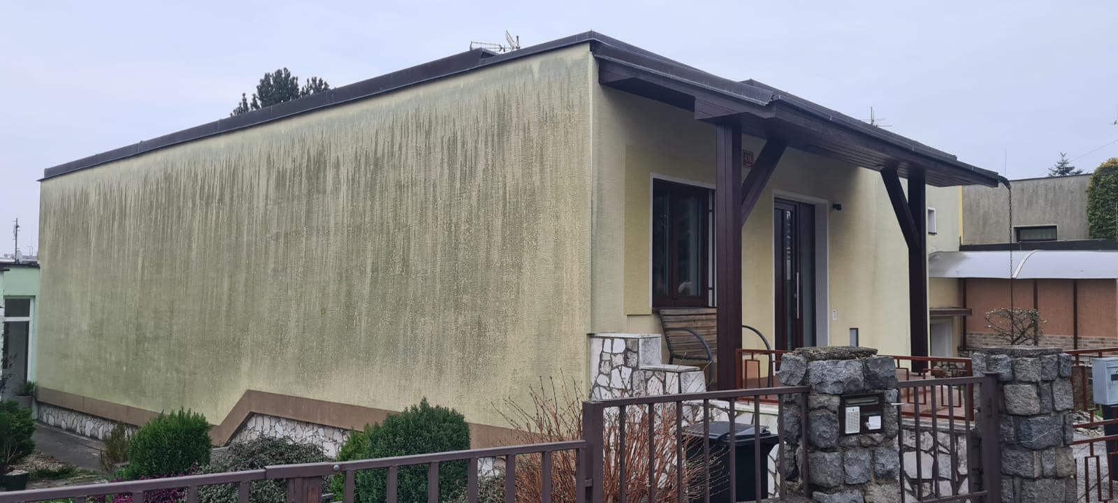 Rodinný dům se zelenými řasami na fasádě před čištěním
